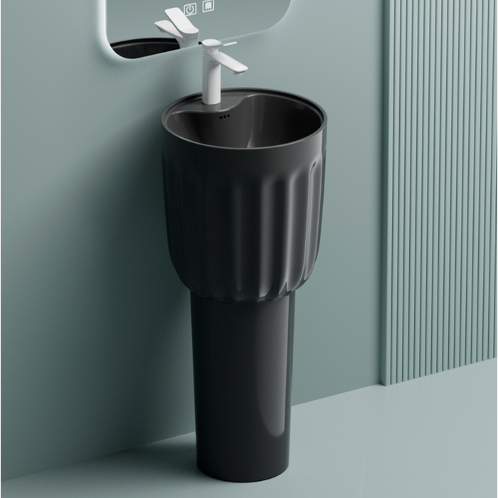 Black freestanding sink with white faucet against a light gray wall.