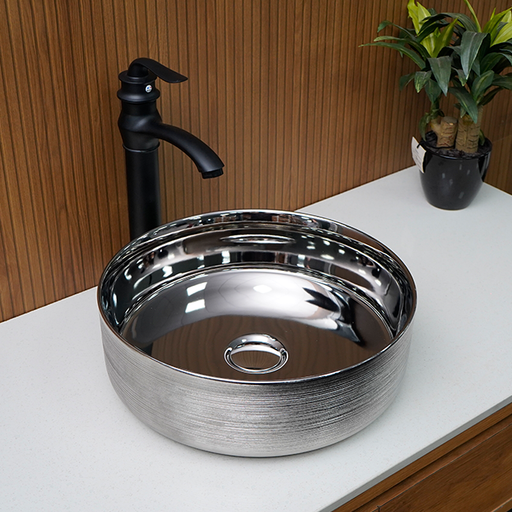 Silver sink with black faucet on a white countertop with a wooden wall background
