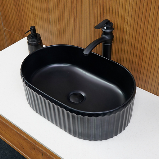 Black ceramic sink with faucet on a wooden wall background