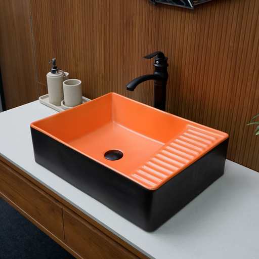 Orange and black rectangular sink on a bathroom counter with wooden wall background