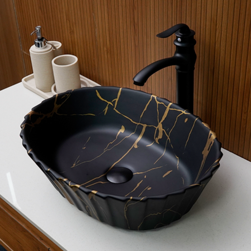 Black ceramic sink with gold accents on a white countertop, featuring a black faucet.