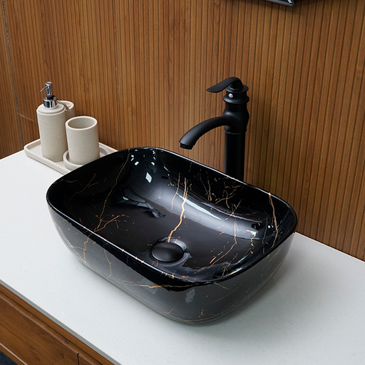 Black ceramic sink with gold accents on a white countertop, featuring a black faucet.
