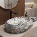 Artificial stone table top wash basin with white and grey marble finish, rugged rock texture and oval design, 500 × 400 × 150 mm.