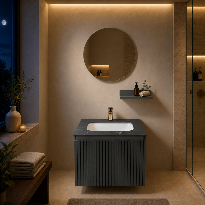 Bassino dark grey wall-mounted bathroom vanity set with fluted cabinet, white inset basin, dark stone countertop, round mirror and utility shelf in a modern luxury bathroom.  