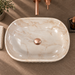 Beige marble ceramic table top wash basin with glossy finish, fluted exterior and elongated oval design, 550 × 350 × 150 mm.