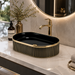 Black and gold luxury table top wash basin with glossy interior, vertical gold detailing and 490 × 320 × 150 mm size for modern bathroom countertops.