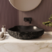Black artificial stone table top wash basin with organic free-form shape, rough rock-textured exterior and 490 × 370 × 140 mm size.