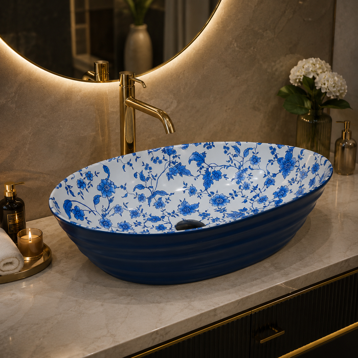 Blue and white floral ceramic table top wash basin with glossy finish, oval designer countertop basin measuring 555 × 355 × 170 mm for modern bathrooms.