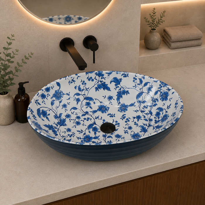 Blue and white floral ceramic table top wash basin with glossy finish, oval designer countertop basin measuring 555 × 355 × 170 mm for modern bathrooms.