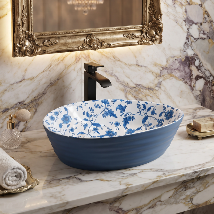 Blue and white floral ceramic table top wash basin with glossy finish, oval designer countertop basin measuring 555 × 355 × 170 mm for modern bathrooms.