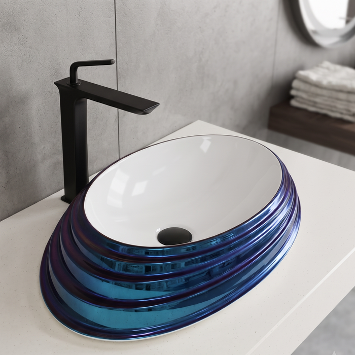 Blue and white glossy ceramic table top wash basin with oval layered design, 520 × 380 × 150 mm designer countertop basin for modern luxury bathrooms.