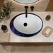 Blue and white glossy ceramic table top wash basin with oval layered design, 520 × 380 × 150 mm designer countertop basin for modern luxury bathrooms.