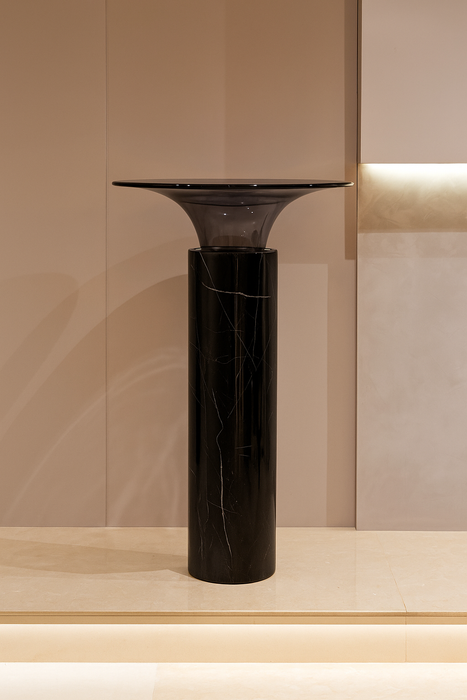 Black marble pedestal against a beige wall