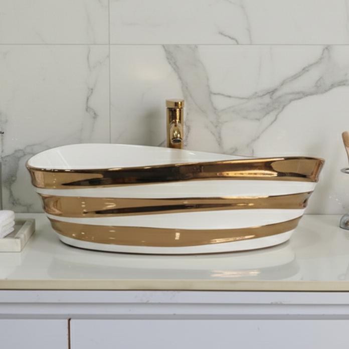 Bathroom vanity with a gold and white basin against a marble wall.