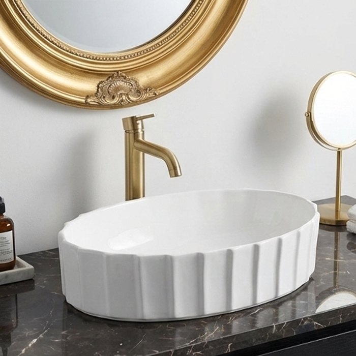 White ceramic sink with gold faucet and mirror in a bathroom setting