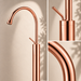 Glossy Rose gold floor mount basin faucet with tall curved spout and single lever handle, modern freestanding bathroom tap for luxury wash basin installations by Bassino.