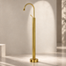 Glossy gold floor mount basin faucet with tall curved spout and single lever handle, modern freestanding bathroom tap for luxury wash basin installations by Bassino.