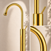 Glossy gold floor mount basin faucet with tall curved spout and single lever handle, modern freestanding bathroom tap for luxury wash basin installations by Bassino.