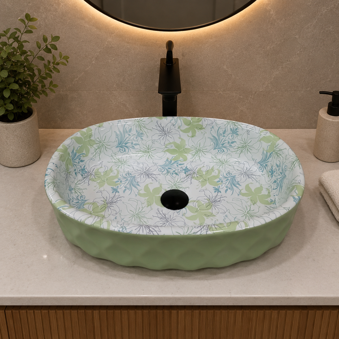 Green blue and white floral ceramic table top wash basin with glossy finish, oval designer countertop basin measuring 500 × 320 × 140 mm for modern bathrooms.