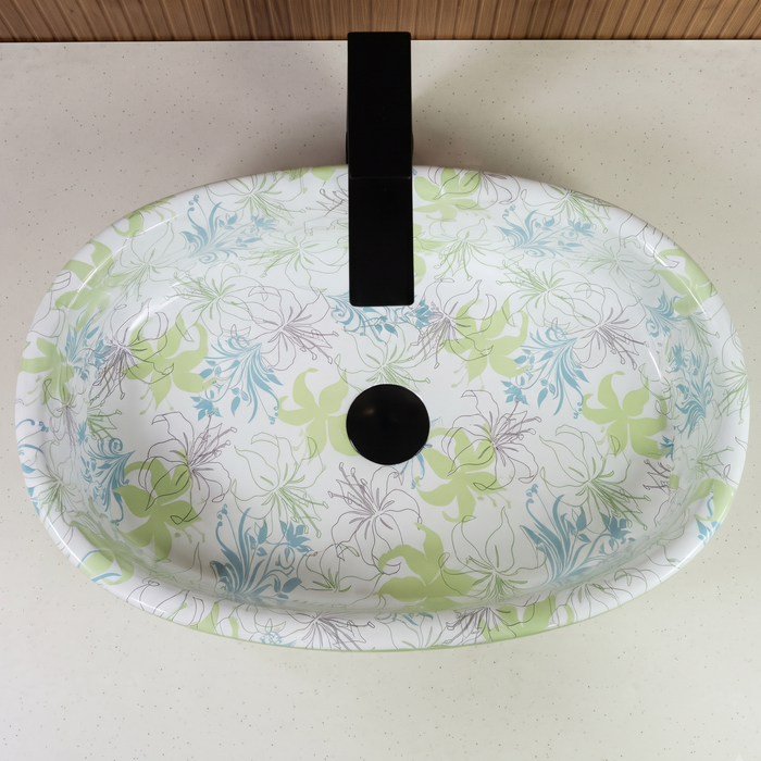 Green blue and white floral ceramic table top wash basin with glossy finish, oval designer countertop basin measuring 500 × 320 × 140 mm for modern bathrooms.