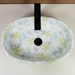 Green blue and white floral ceramic table top wash basin with glossy finish, oval designer countertop basin measuring 500 × 320 × 140 mm for modern bathrooms.