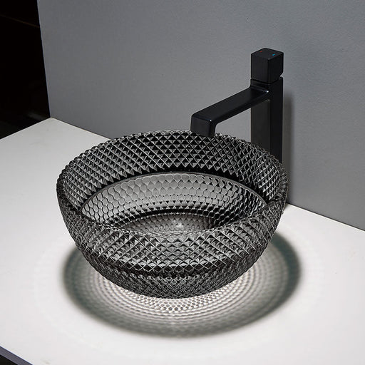 Black textured sink with black faucet on a white countertop against a gray wall.