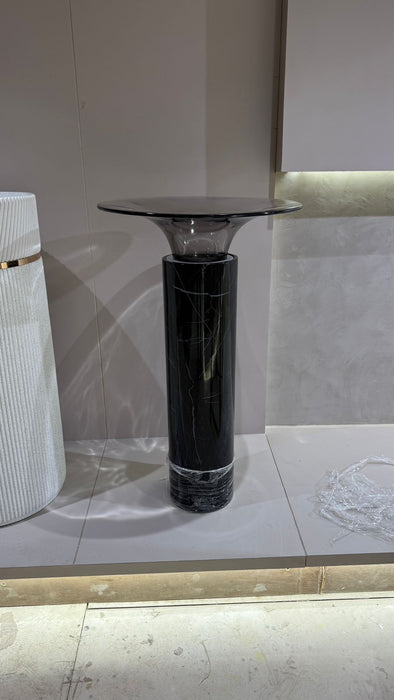 Modern black marble pedestal sink against a tiled wall.
