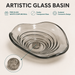 Smoky transparent glass table top wash basin with sculpted concentric design, matching glass waste coupling ball and 450 × 320 × 130 mm dimensions.