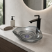 Smoky transparent glass table top wash basin with sculpted concentric design, matching glass waste coupling ball and 450 × 320 × 130 mm dimensions.