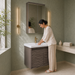 Wall-mounted bronze-grey bathroom vanity set with wave-textured cabinet doors, white basin, mirrored storage cabinet, and integrated LED lighting.