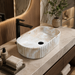White and beige marble-finish table top wash basin with fluted exterior design, rounded rectangular shape and 510 × 310 × 120 mm size.