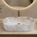 White and beige marble-finish table top wash basin with fluted exterior design, rounded rectangular shape and 510 × 310 × 120 mm size.