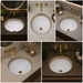 White and gold designer ceramic under counter wash basin with glossy finish, 490 × 400 × 200 mm oval undermount bathroom basin with decorative gold border pattern.