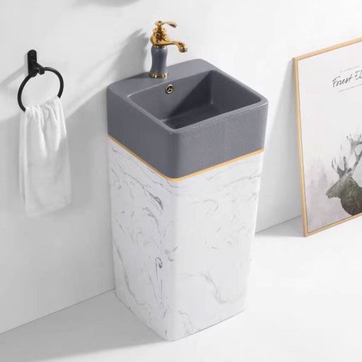 Gray ceramic sink with gold faucet in a bathroom setting, featuring a framed picture of a deer.